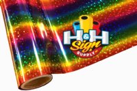 The image shows a close-up view of a rainbow textile foil. The foil features a shiny, metallic surface with holographic stars arranged in a random pattern on top of the rainbow stripes.
